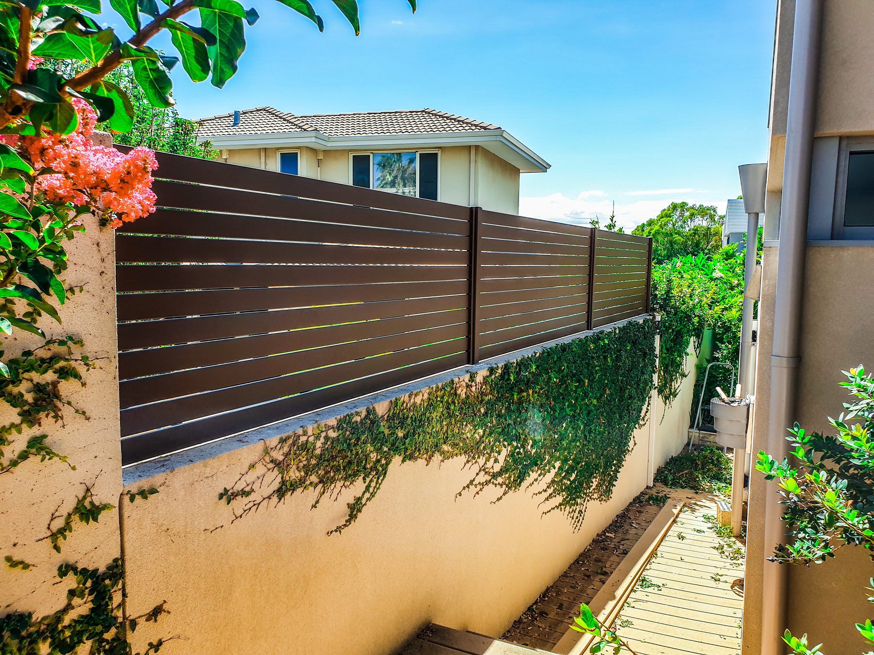 Timber look aluminium slat fencing above a rendered wall in Perth