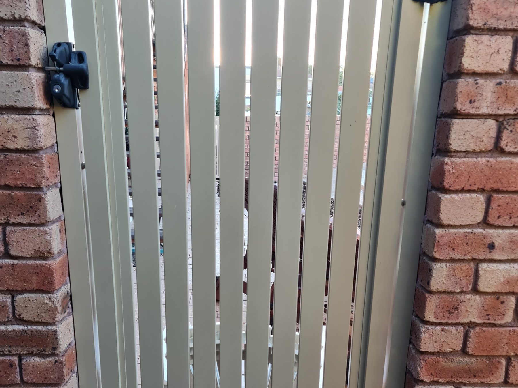Aluminium slatted gate between brick piers in Perth