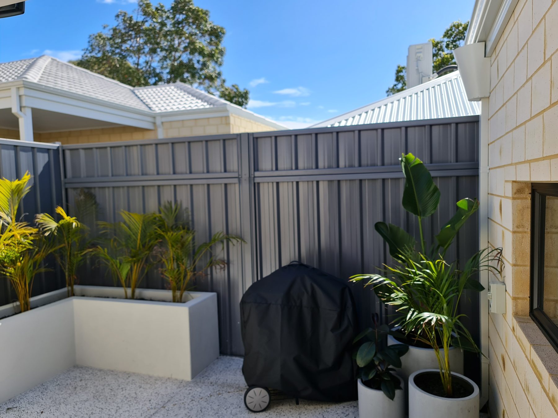 Charcoal Colorbond boundary fencing with garden planters in Perth
