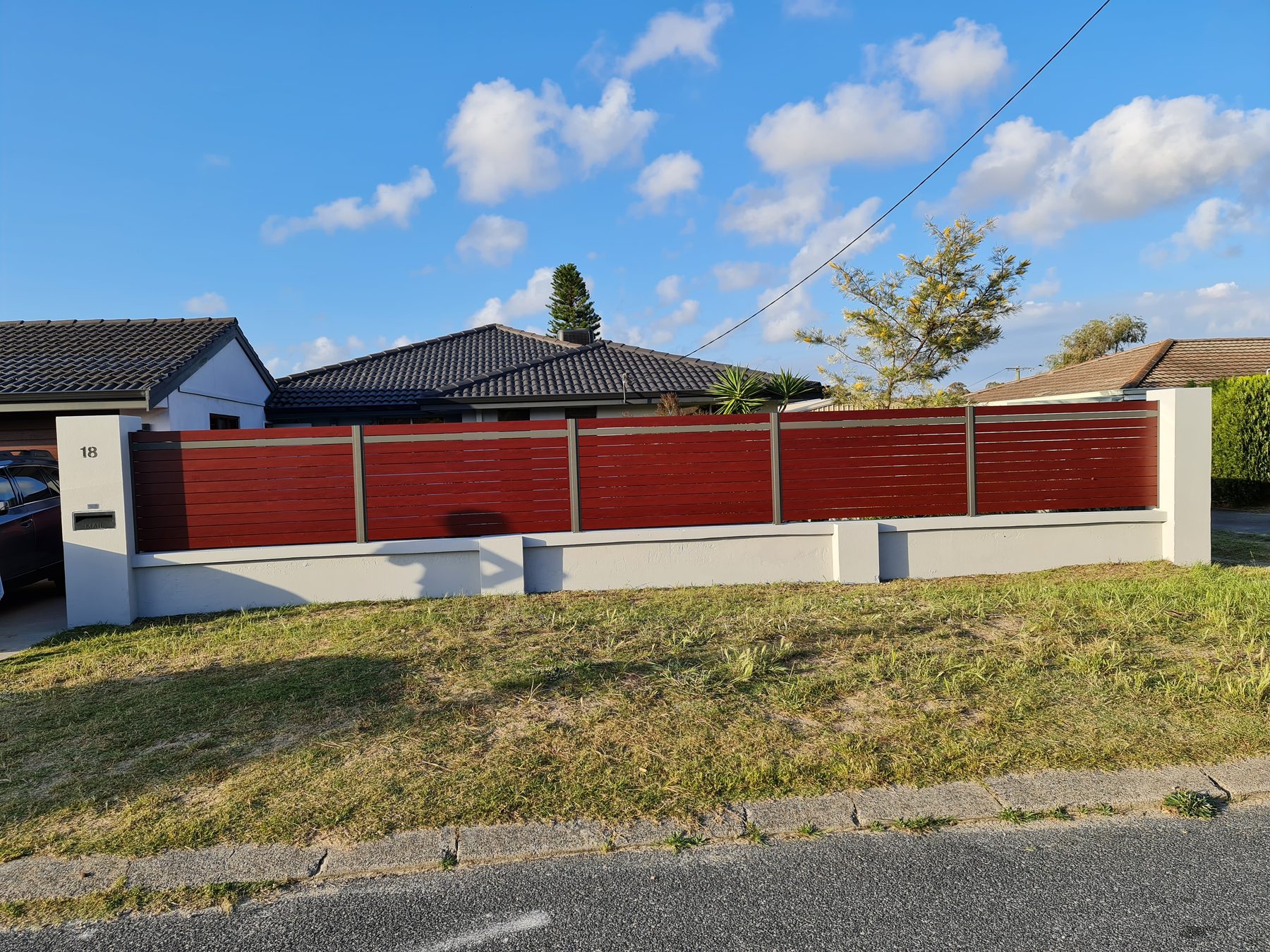 Red Colorbond fencing above a limestone retaining wall in Perth