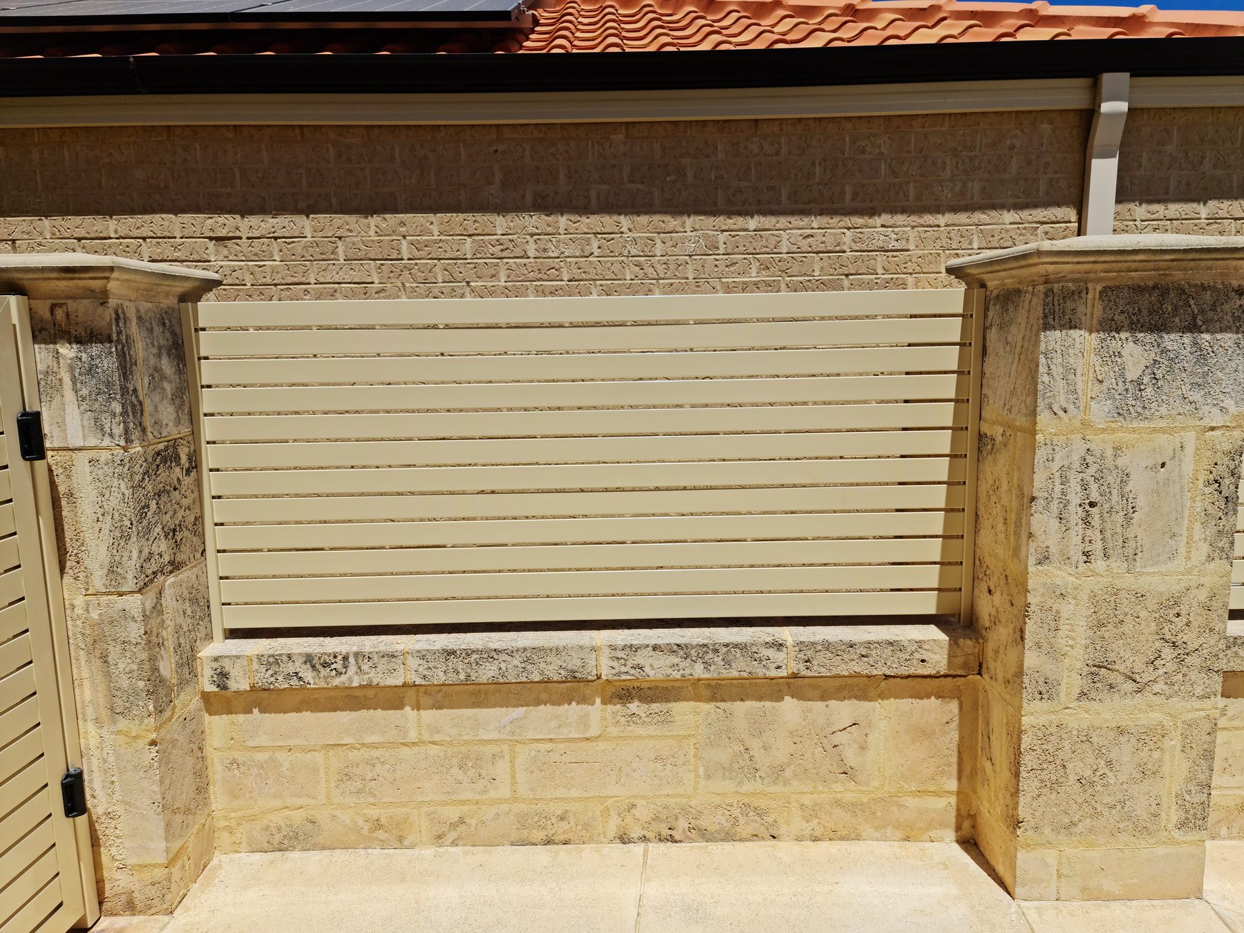 Cream aluminium slat fencing infill panel between limestone piers, Perth